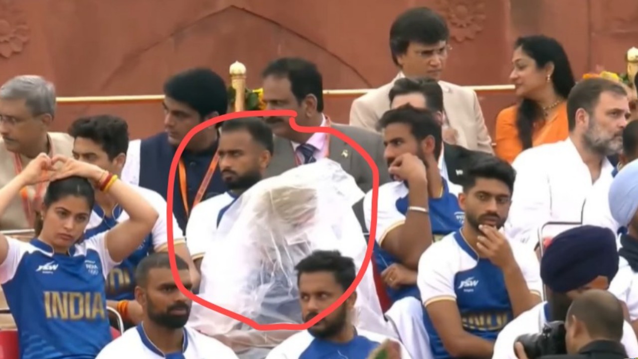 Who is person sitting covered polythene Side Of Manu Bhaker